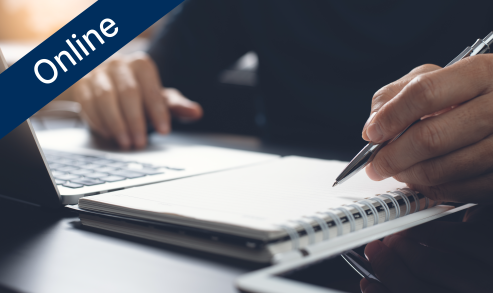 Person writing in notepad next to computer